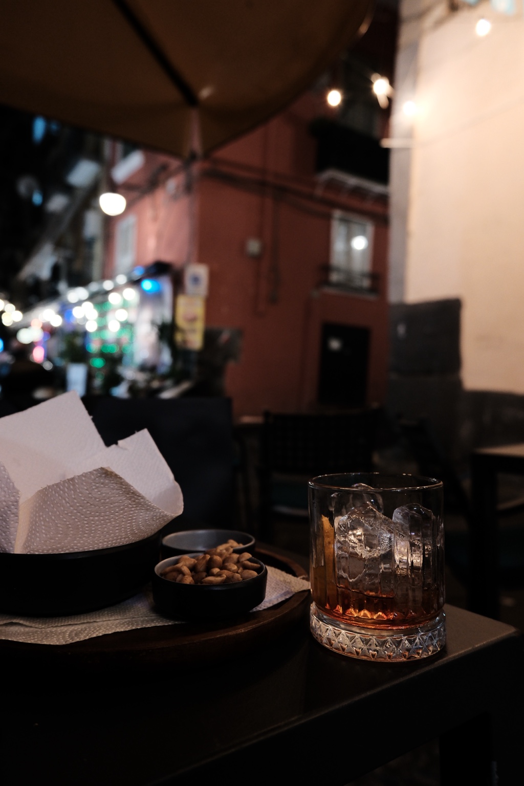 A half-finished Negroni and small bowls of snacks on a dimly lit terrace in Napoli